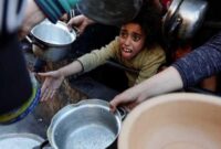 Seorang anak Palestina antre untuk menerima makanan selama bulan suci Ramadan, saat konflik antara Israel dan Hamas berlanjut, di Rafah, di selatan Jalur Gaza 13 Maret 2024. REUTERS/Mohammed Salem